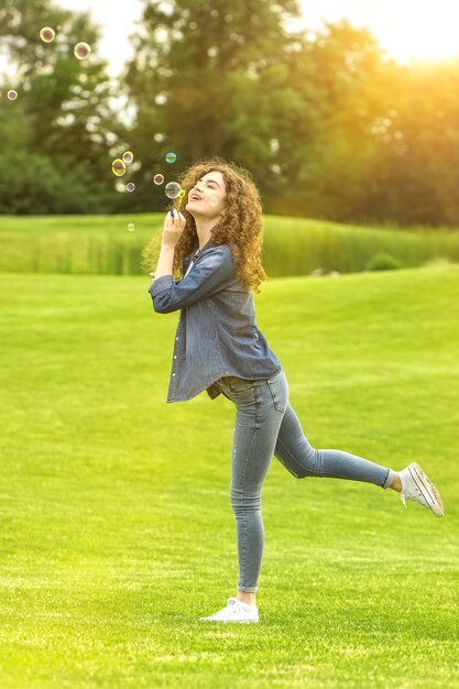La donna felice che fa le bolle nel parco verde