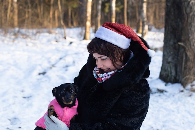 The happy woman in a body in nature in winter with a dog