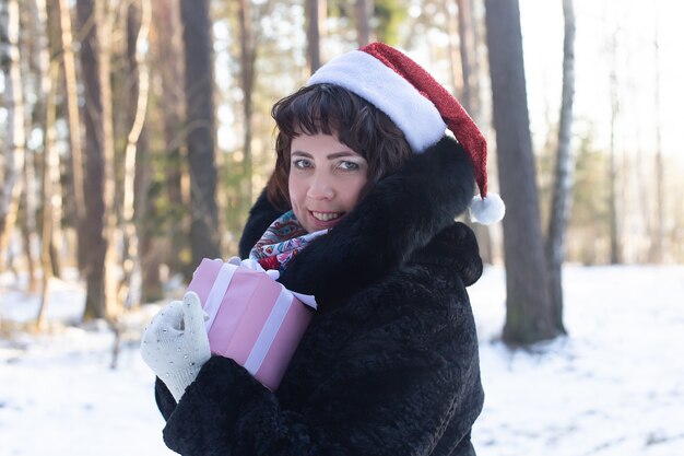 贈り物を持った冬の自然の中で幸せな女性、Christma
