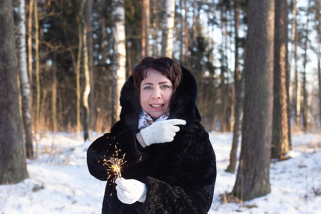 Donna felice nel corpo in natura in inverno con stelle filanti, natale