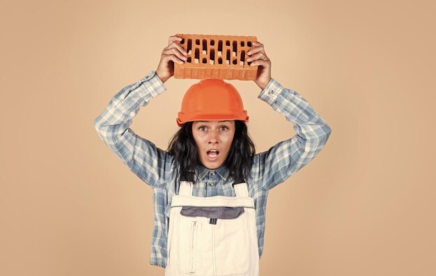 Happy woman builder in protective helmet use brick architecture