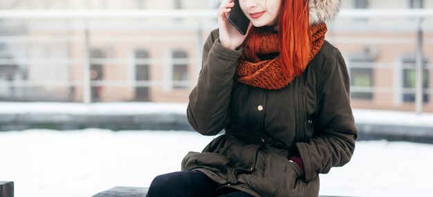 Happy woman calling on the mobile phone  in the street in winter