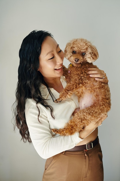 Photo happy woman carrying little dog