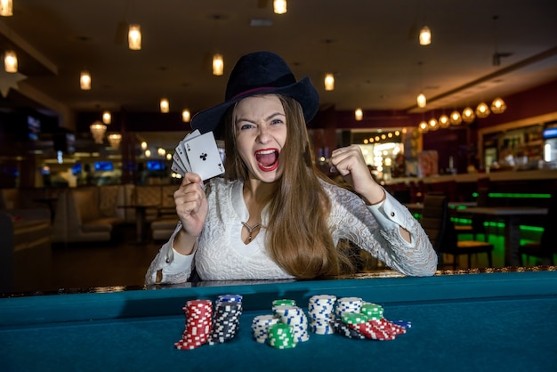 Happy woman in casino holding four aces