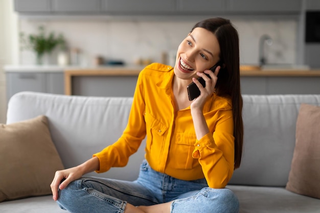 Photo happy woman chatting on phone relaxed on couch