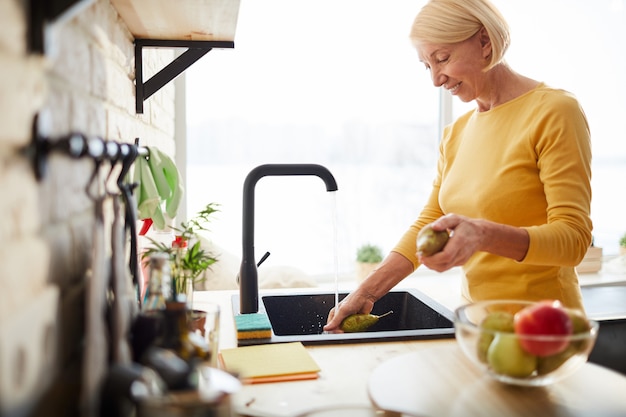 Happy woman cleaning fruits