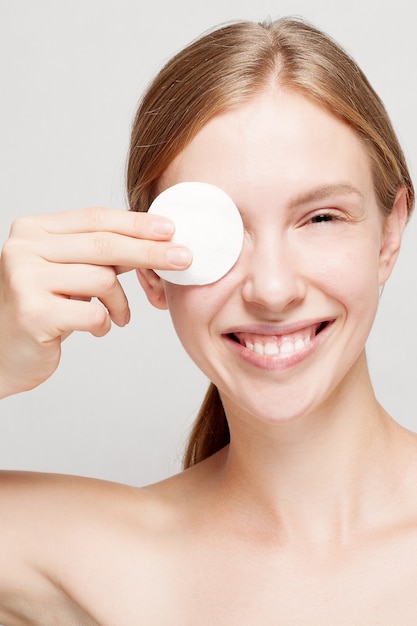 Happy woman cleaning her face with cotton pads