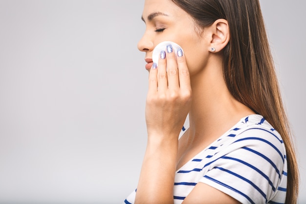 Happy woman cleaning her face with cotton pads