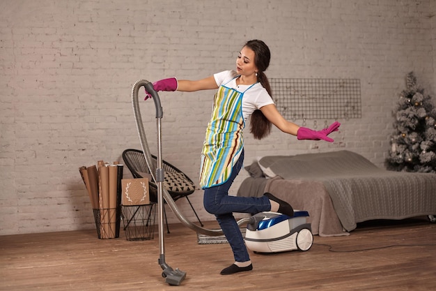 Happy woman cleaning home,dancing with vacuum cleaner and having fun, copy space.