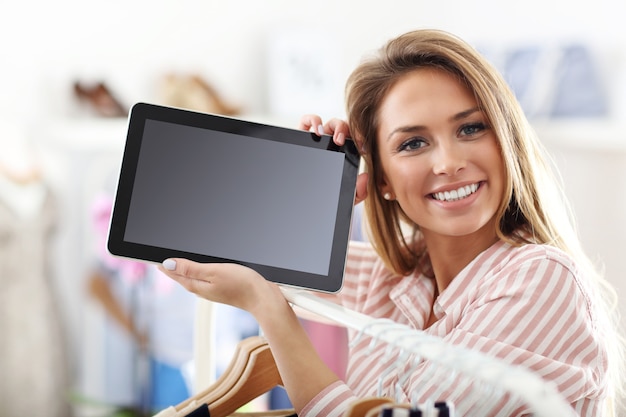 happy woman in clothes shop holding tablet
