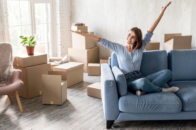 Happy woman on the couch moving out with boxes ready