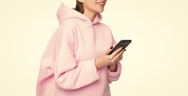 Фото Счастливая женщина в розовом капюшоне с смартфоном изолирована в белой социальной сети