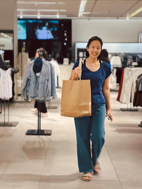 Foto donna felice che fa la spesa di vestiti e tiene in mano la borsa di carta del prodotto