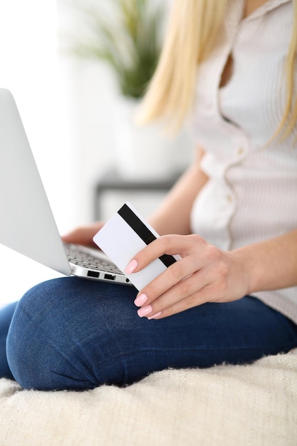 Счастливая женщина делает покупки в Интернете дома Крупным планом рука держит кредитную карту рядом с ноутбуком