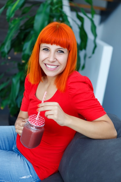 Happy woman drinking a blueberry smoothie at home