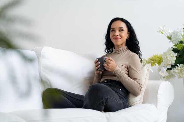 Photo happy woman drinking coffee on a sofa at home for crucial rest and relaxation