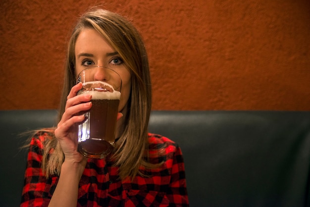 Photo happy woman drinking light lager beer in pab and looking. vintage portrait