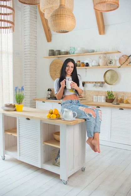 Donna felice che beve il tè in cucina a casa