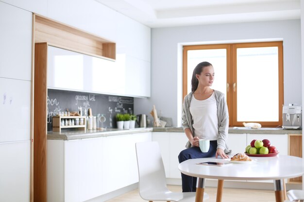Happy woman drinking tea in the kitchen at home