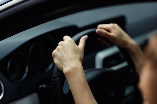 Happy woman driver hands close up holds steering wheel car