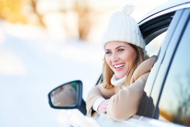 雪の降る冬に車を運転する幸せな女性。高品質の写真