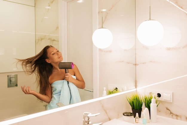 Happy woman drying long hair in bathroom