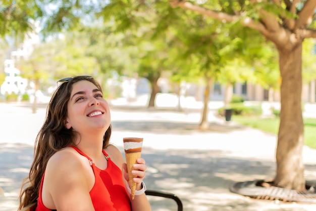 Happy woman eating Ice cream cone at park in sunny day