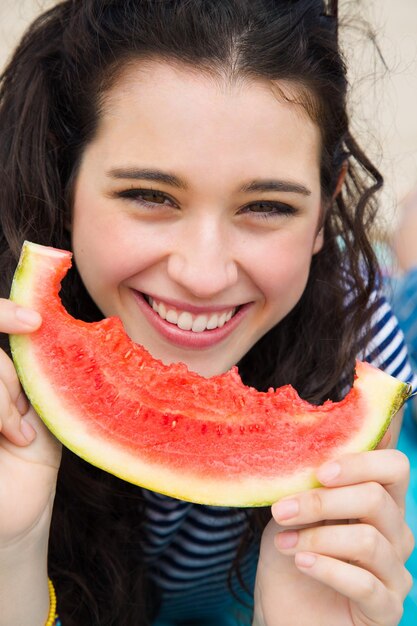 Foto donna felice che mangia cocomero sulla spiaggia