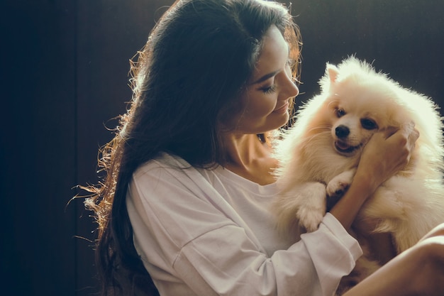 白いポメラニアンの犬を抱擁している幸せな女性