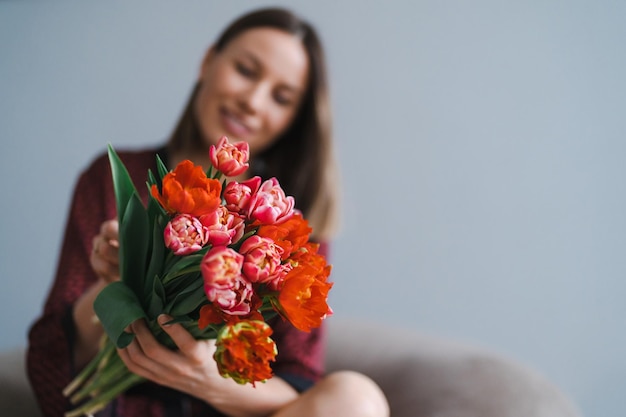 幸せな女性はチューリップの花束を楽しむ花の束とキッチンのインテリアを楽しむ主婦甘い家アレルギー無料