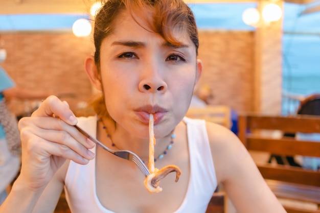 Happy woman enjoy eating squid seafood in the summer vacation