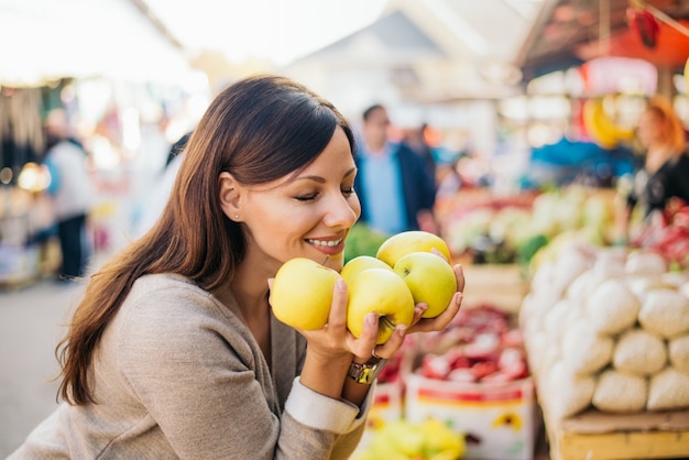 Donna felice che gode dell'odore fresco di paprica al mercato.