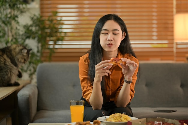 Happy woman enjoying in weekend eating pizza for lunch in cozy living room