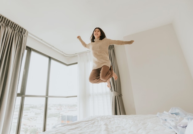 Счастливая женщина взволнована, прыгает на своей кровати
