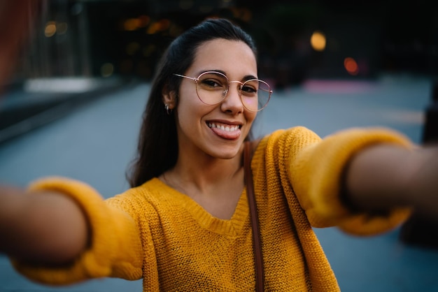 Happy woman in eyeglasses taking selfie