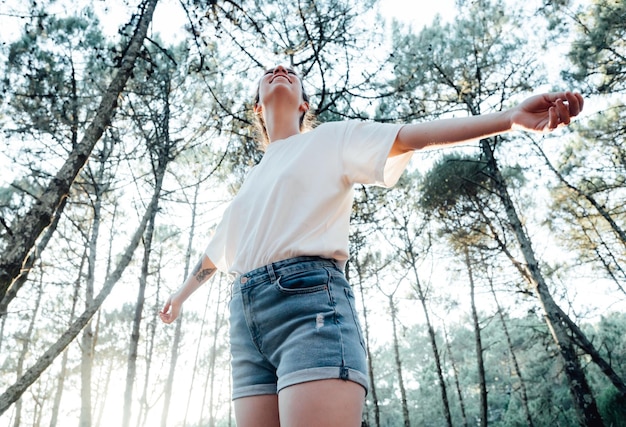 Happy woman in forest with open arms from behind breathing clean air Environment no pollution healthy natural living lifestyle Nature is where she loves to wonderFree spirit in the woods