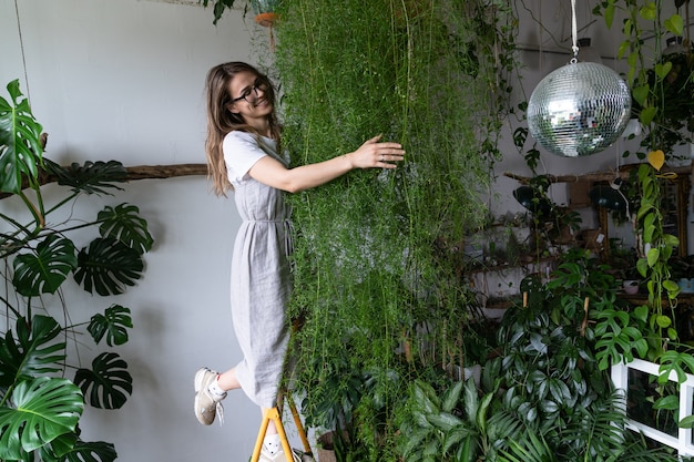 自宅でアスパラガス観葉植物を受け入れる幸せな女性の庭師屋内居心地の良い庭の趣味の概念