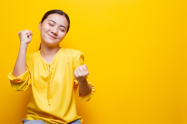 Happy woman gesturing against yellow background