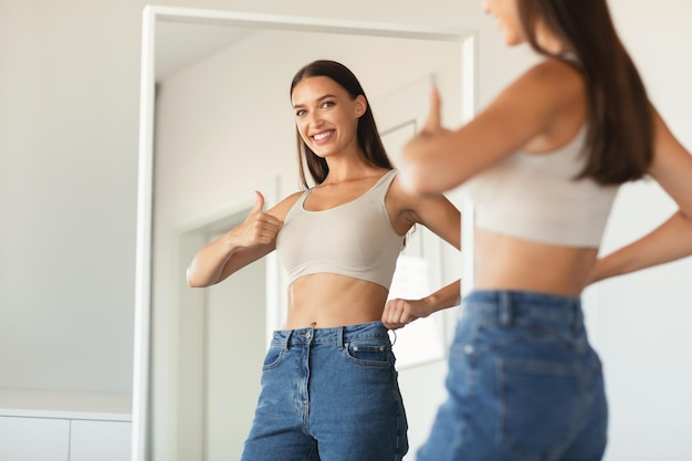 Photo happy woman gesturing thumbs up approving new size at home