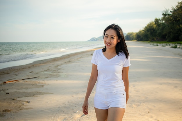 행복 한 여자는 해변에서 산책을 간다.