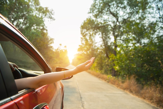 Счастливая женщина передает окно автомобиля красный с солнечным светом