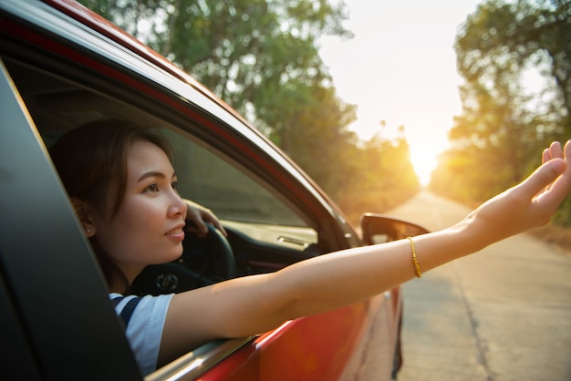 幸せな女性は日光で赤い窓の車を配る