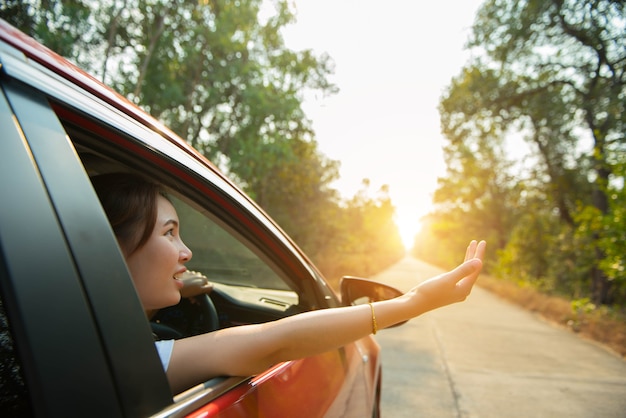 写真 幸せな女性は日光で赤い窓の車を配る