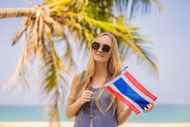 Happy woman having fun at the beach with Thailand flag Beautiful girl enjoying travel to Asia