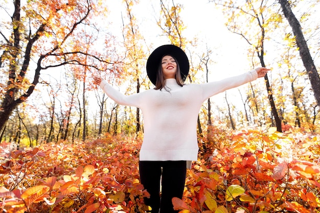 Happy woman having fun in park on autumn sunny day