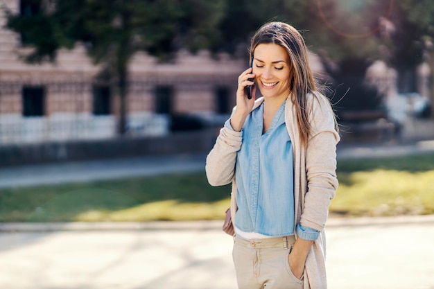 A happy woman having a phone call in a park