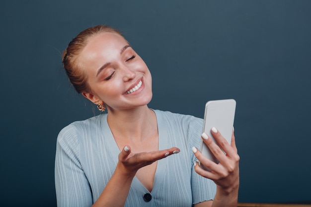 Счастливая женщина, имеющая видеозвонок по мобильному телефону, красивая улыбающаяся молодая женская студия стрелять моделью