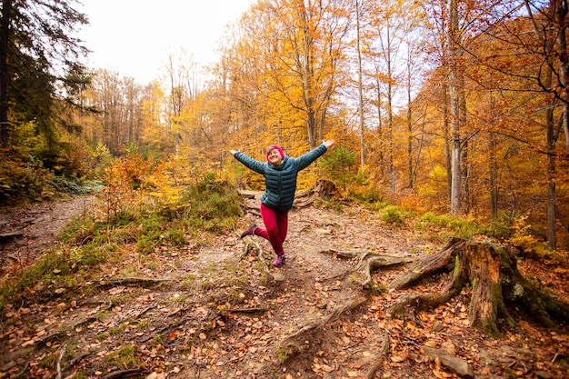 Happy woman hiker is walking in the beautiful autumn forest