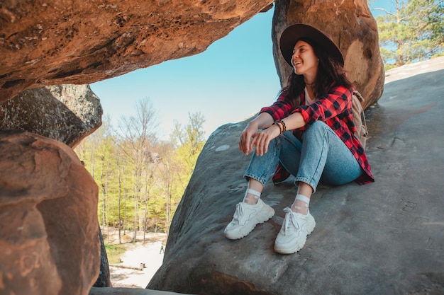 Happy woman hiker sitting at the rock