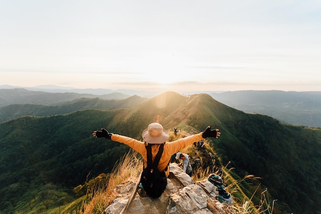 Photo happy woman hiking and sitting on top mountain at khao chang phuak, thongphaphoom national park, kanchanaburi province, thailand. subject is blurred, noise and color effect.